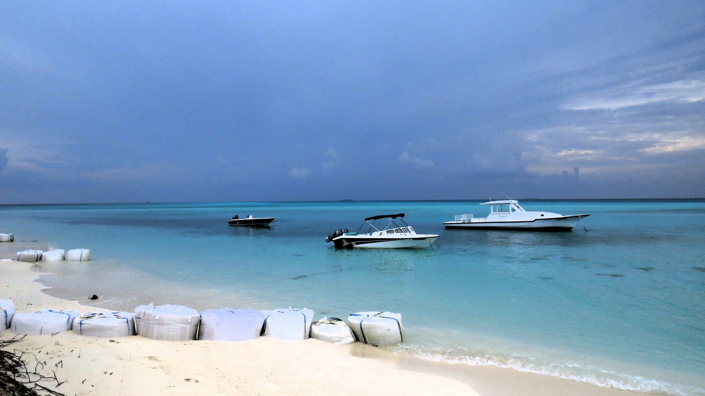 Beach on Fulidhoo, Vaavu Atoll, with boats anchored in the lagoon